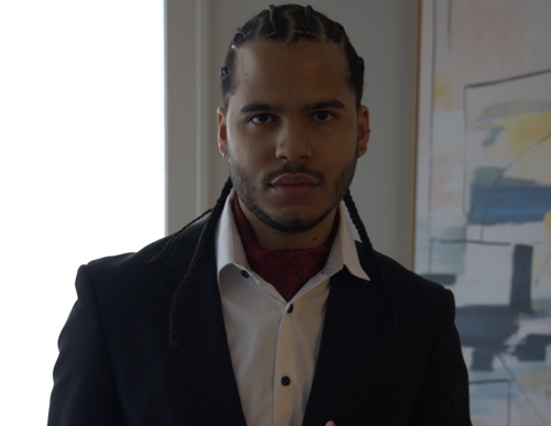 Joshua H. Jimenez, host, in a black suit jacket and white dress shirt